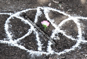 Eine rosa Rosenblüte wurde in das Zentrum des Serch-Bythol-Symbols gelegt. Die offene Seite der Blüte ist nach oben, also zum Baum, gerichtet.